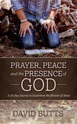 Man in blue jeans and blue flannel shirt with bracelet on right arm and watch on the other arm is kneeling in prayer with Bible on ground in wooded area for peace and the presence of God.