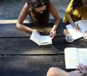 One woman is sleveless blouse and another in yellow longsleve blouse with a man sitting on outside pick nick table studying the Simple and Vivid Parables of Jesus DVD Bible Study.