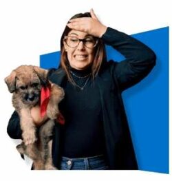 Lady standing up wearing black sweater holding her small dog under her arm ready to start Dog Training.