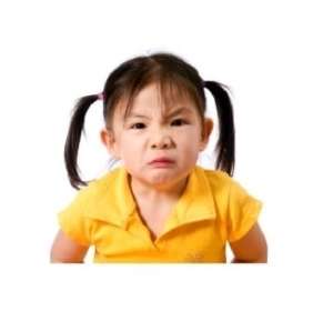 Angry little girl with black pony tales and yellow shirt