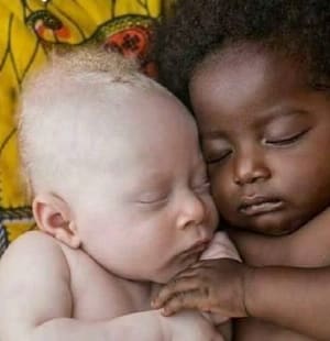 African-america and white infant babies laying side by side cuddling showing love or affection signifying God Made Me and You.