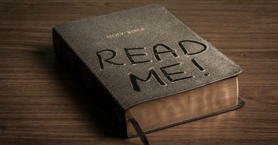Bible with "READ ME!" written on the cover, on a wooden table. How to decipher the Bible.