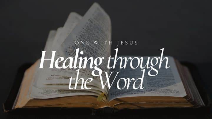 An open Bible with pages fanned out, displaying the text "Healing through the Word" and "ONE WITH JESUS" in white lettering against a dark, moody background, suggesting spiritual comfort and guidance.