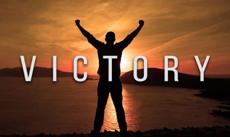 Silhouette of person with arms raised at sunset; text reads "VICTORY